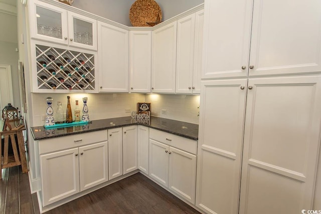 kitchen featuring dark wood finished floors, white cabinets, dark stone countertops, and tasteful backsplash