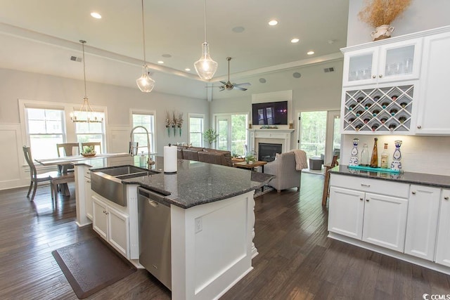 kitchen featuring a sink, a fireplace, ceiling fan with notable chandelier, tasteful backsplash, and stainless steel dishwasher