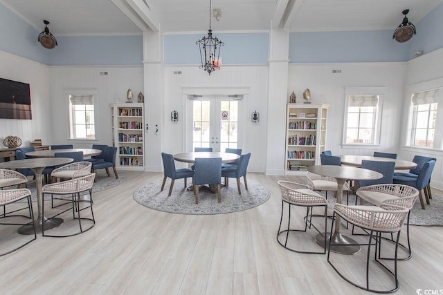 dining room with a healthy amount of sunlight, beamed ceiling, french doors, and light wood-type flooring