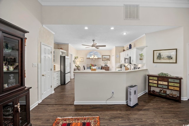 9628 Indigo Creek Blvd, Murrells Inlet, SC 29576 - kitchen featuring visible vents, white cabinets, freestanding refrigerator, a peninsula, and dark wood-style floors