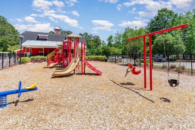 communal playground featuring fence and view of scattered trees