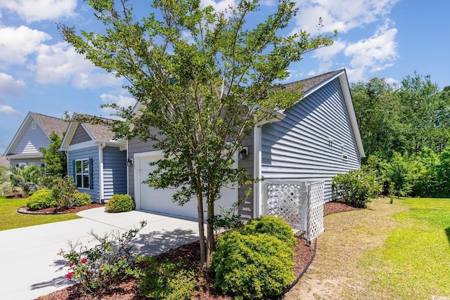 view of side of home featuring a garage, driveway, and a yard