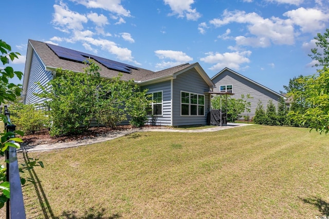 5581 Plantersville Pl, Myrtle Beach, SC 29579 - back of house featuring roof mounted solar panels, roof with shingles, and a lawn
