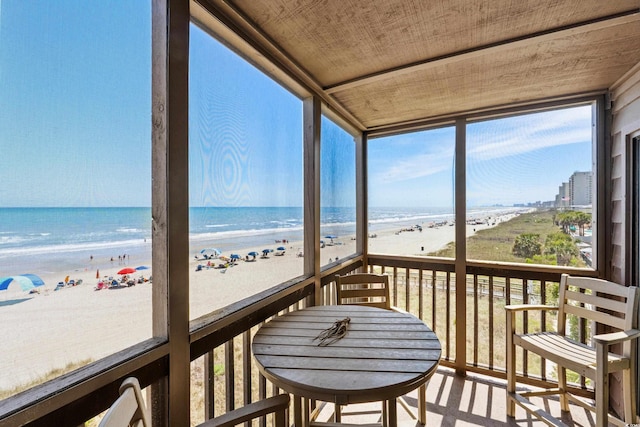 sunroom with a beach view, plenty of natural light, and a water view
