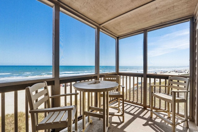 unfurnished sunroom featuring a beach view and a water view
