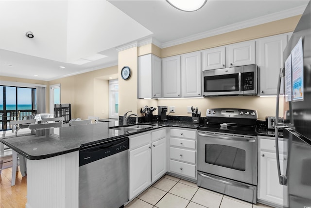 kitchen with appliances with stainless steel finishes, a sink, a peninsula, a healthy amount of sunlight, and ornamental molding