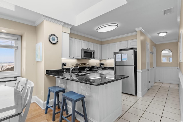 kitchen featuring appliances with stainless steel finishes, ornamental molding, a peninsula, and visible vents