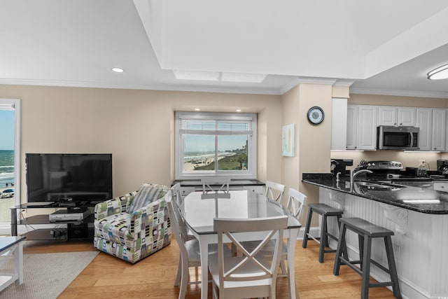 kitchen with ornamental molding, stove, stainless steel microwave, and light wood finished floors