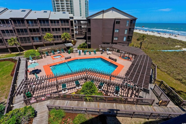 community pool featuring a water view, a patio area, and a beach view