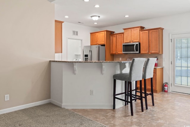 853 Derbyshire Ct, Conway, SC 29526 - kitchen featuring stainless steel appliances, a kitchen bar, stone counters, brown cabinets, and recessed lighting