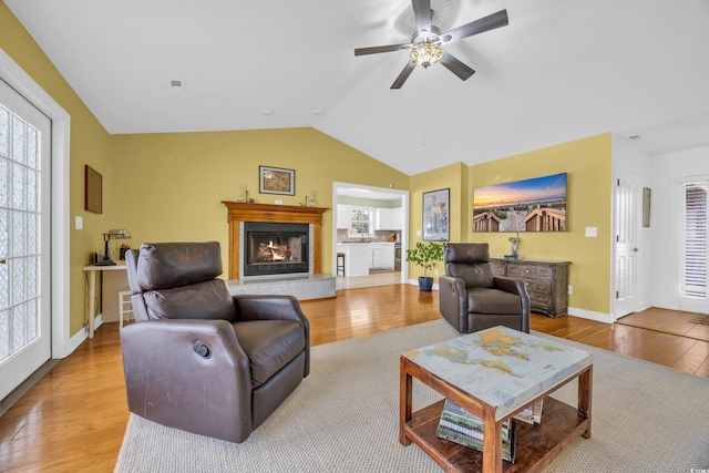 living room with wood finished floors, a premium fireplace, a healthy amount of sunlight, ceiling fan, and lofted ceiling
