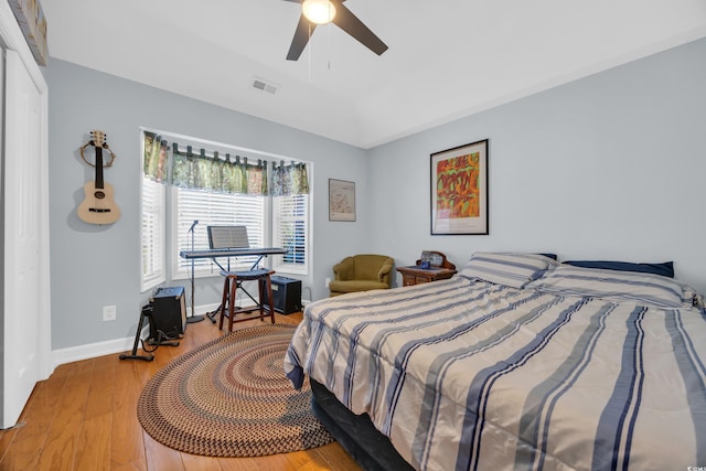 bedroom featuring a ceiling fan, baseboards, visible vents, wood finished floors, and a raised ceiling