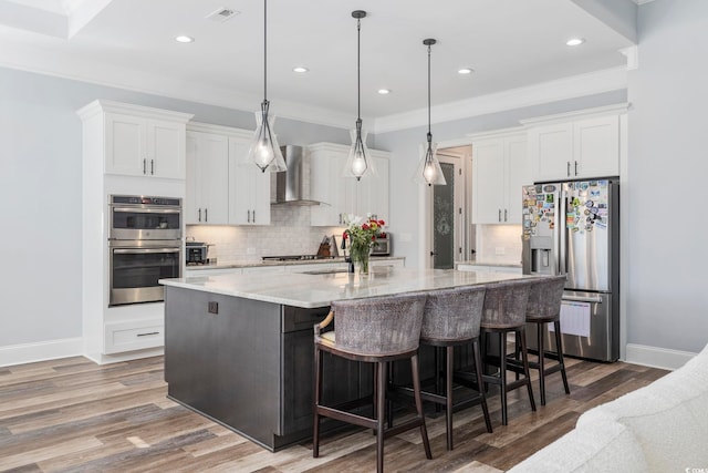 kitchen with wall chimney range hood, tasteful backsplash, stainless steel appliances, and white cabinetry