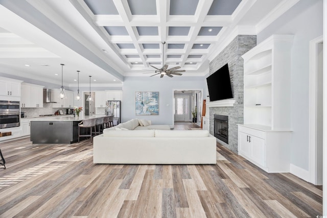 living room with beam ceiling, a stone fireplace, light wood-style floors, recessed lighting, and a ceiling fan
