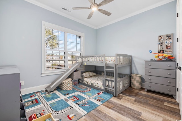 bedroom featuring baseboards, ornamental molding, wood finished floors, and visible vents