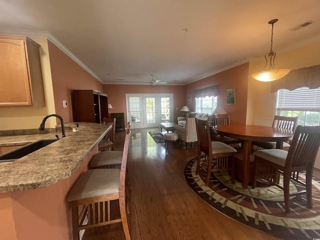 dining area with a healthy amount of sunlight, crown molding, visible vents, and dark wood-type flooring