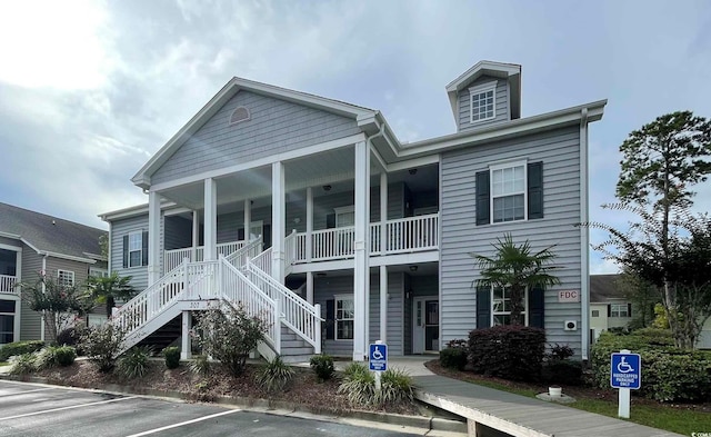view of front of home featuring a porch, uncovered parking, and stairs