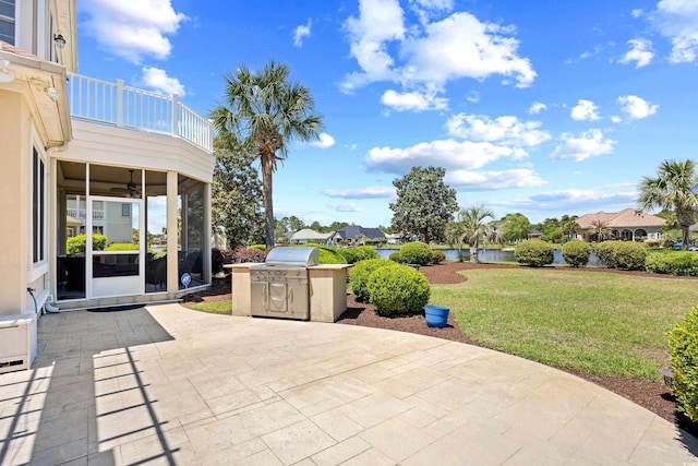 view of patio / terrace with a ceiling fan, exterior kitchen, a sunroom, a balcony, and a water view