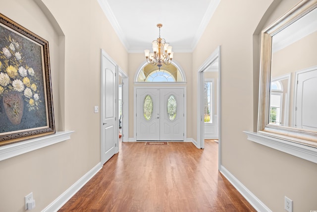 foyer featuring crown molding, baseboards, a notable chandelier, and wood finished floors