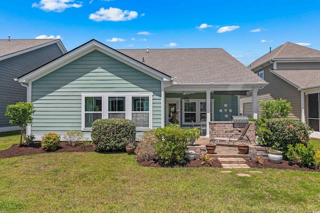 back of property with a patio, a shingled roof, and a yard