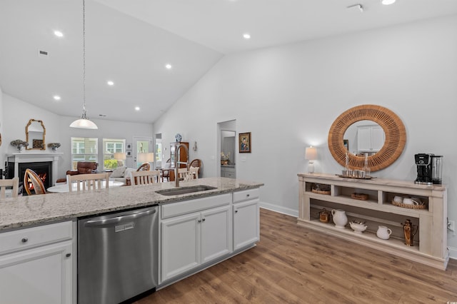 kitchen with light stone countertops, light wood-type flooring, white cabinetry, a sink, and dishwasher