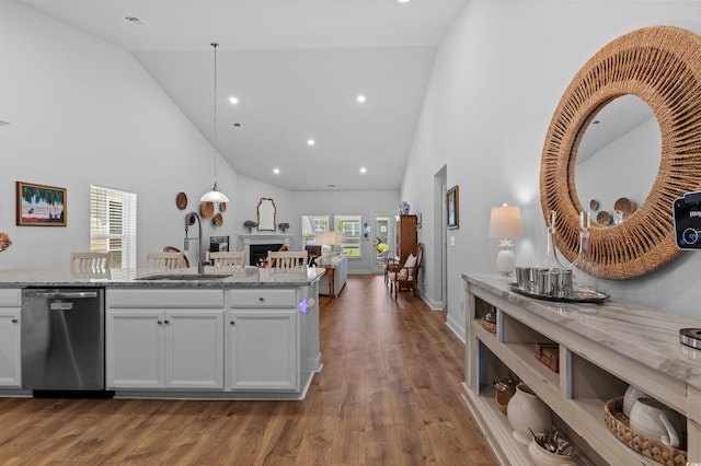 kitchen with high vaulted ceiling, a lit fireplace, a sink, and dishwasher