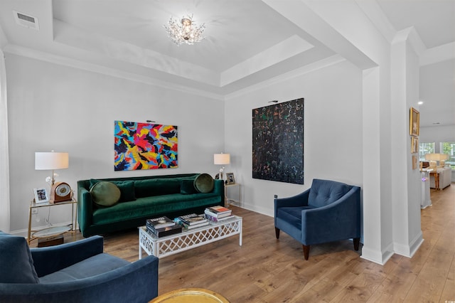 living room featuring a chandelier, baseboards, a tray ceiling, visible vents, and hardwood / wood-style flooring