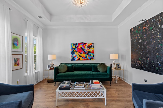 living area featuring baseboards, a tray ceiling, hardwood / wood-style flooring, and visible vents
