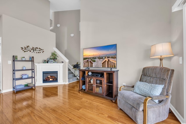 260 Connemara Dr Unit E, Myrtle Beach, SC 29579 - living area with a high ceiling, a glass covered fireplace, baseboards, wood finished floors, and stairway
