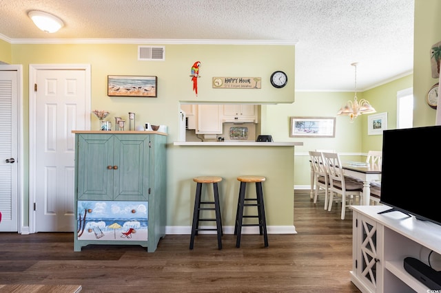 609 Hillside Dr S Unit C-10, North Myrtle Beach, SC 29582 - kitchen with dark wood finished floors, a textured ceiling, a chandelier, a breakfast bar area, and crown molding