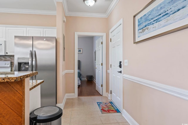 doorway to outside with ornamental molding, light tile patterned floors, and baseboards