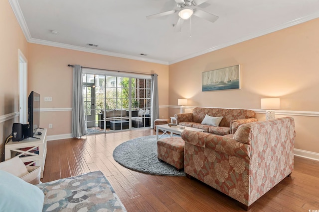 living area featuring hardwood / wood-style floors, ceiling fan, baseboards, and crown molding