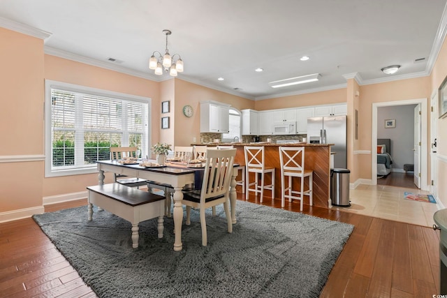 dining room featuring a chandelier, healthy amount of natural light, ornamental molding, hardwood / wood-style floors, and baseboards