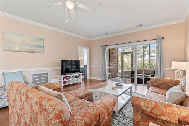 living area featuring wood finished floors, ornamental molding, a ceiling fan, and baseboards