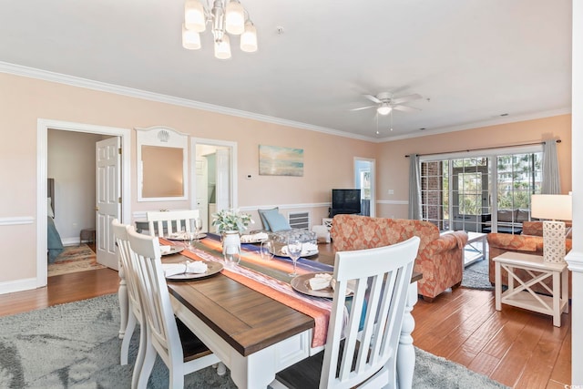dining space with wood finished floors, ornamental molding, a chandelier, ceiling fan, and baseboards