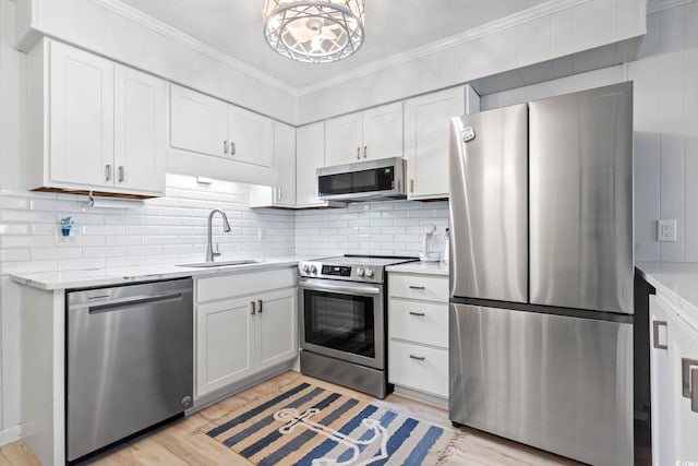 kitchen with crown molding, appliances with stainless steel finishes, a sink, and light countertops