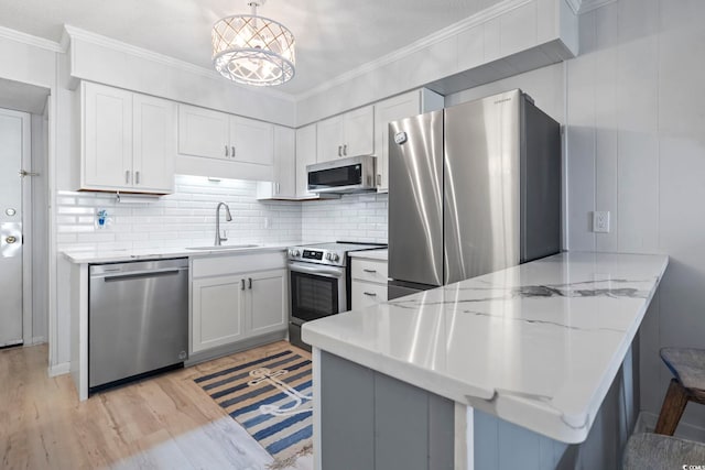 kitchen with a sink, stainless steel appliances, a peninsula, backsplash, and ornamental molding