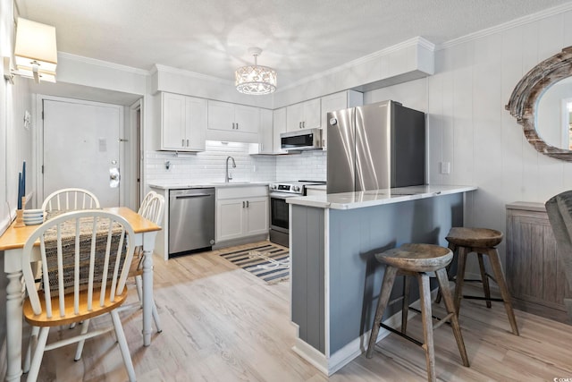 kitchen featuring light wood-type flooring, a sink, a peninsula, a breakfast bar, and stainless steel appliances