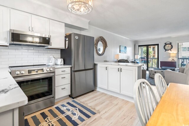 kitchen with open floor plan, appliances with stainless steel finishes, white cabinets, and ornamental molding