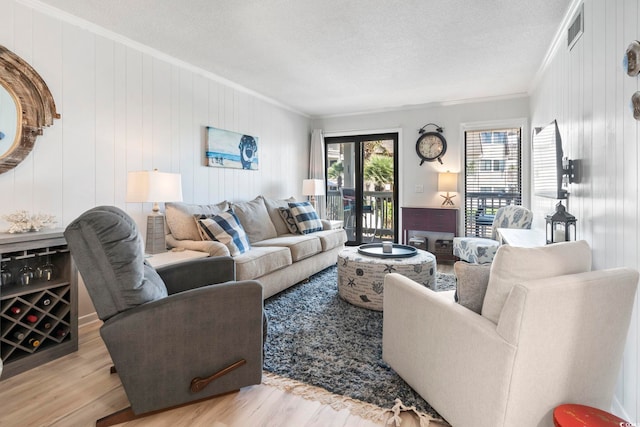 living room featuring crown molding, a textured ceiling, wood finished floors, and visible vents
