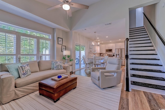 living area with visible vents, stairs, ceiling fan with notable chandelier, and light wood finished floors