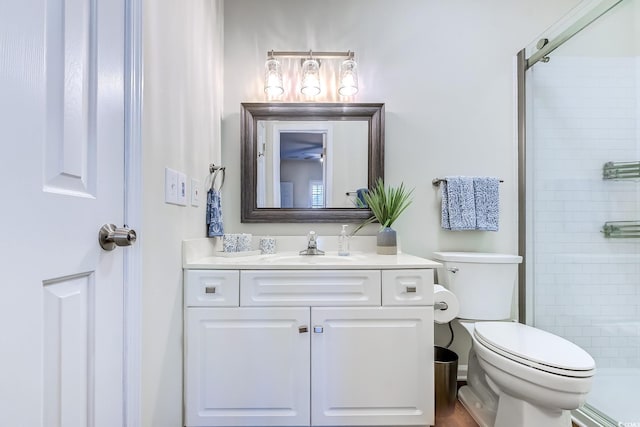 bathroom featuring toilet, a shower stall, and vanity
