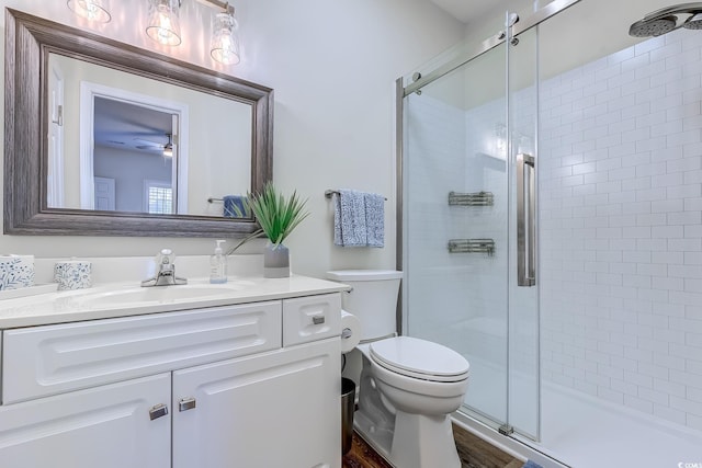 full bath with vanity, toilet, a ceiling fan, and a stall shower