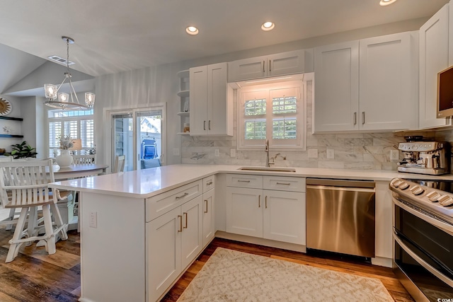 kitchen featuring visible vents, a peninsula, light countertops, a sink, and appliances with stainless steel finishes