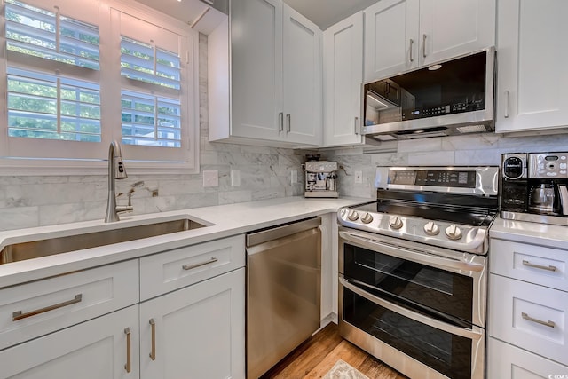 kitchen with a sink, appliances with stainless steel finishes, tasteful backsplash, and light countertops