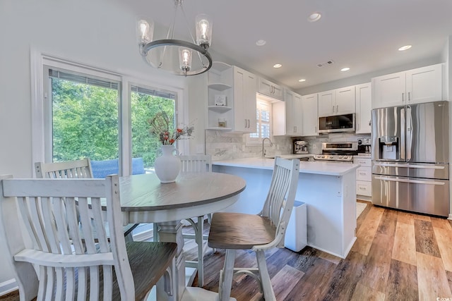 kitchen with open shelves, light countertops, a chandelier, stainless steel appliances, and a peninsula