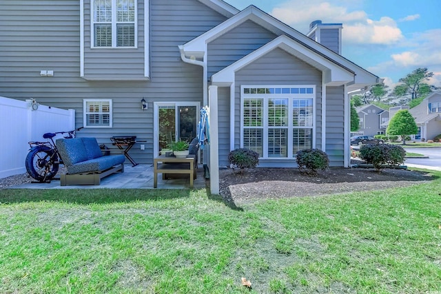 back of property featuring a patio, outdoor lounge area, a yard, and a chimney