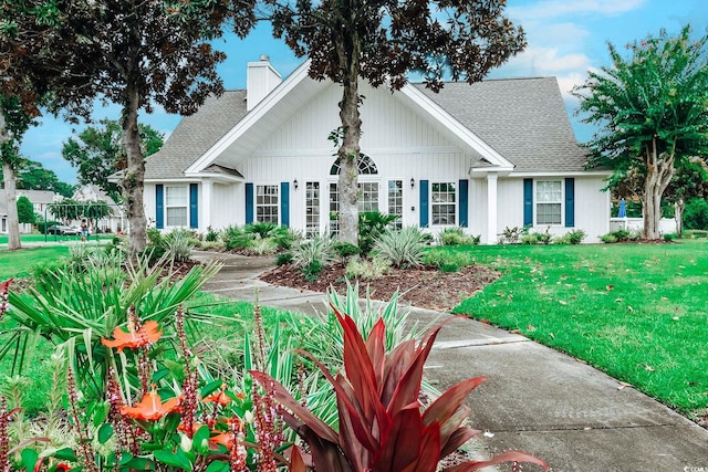 view of front of property featuring a chimney, roof with shingles, and a front yard