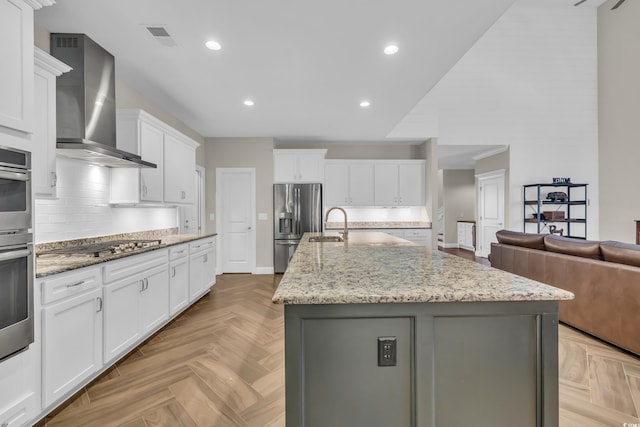 1136 Doubloon Dr, North Myrtle Beach, SC 29582 - kitchen with a kitchen island with sink, wall chimney exhaust hood, white cabinetry, tasteful backsplash, and appliances with stainless steel finishes