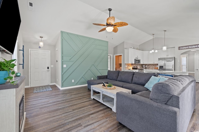 living area featuring a ceiling fan, arched walkways, wood finished floors, and vaulted ceiling